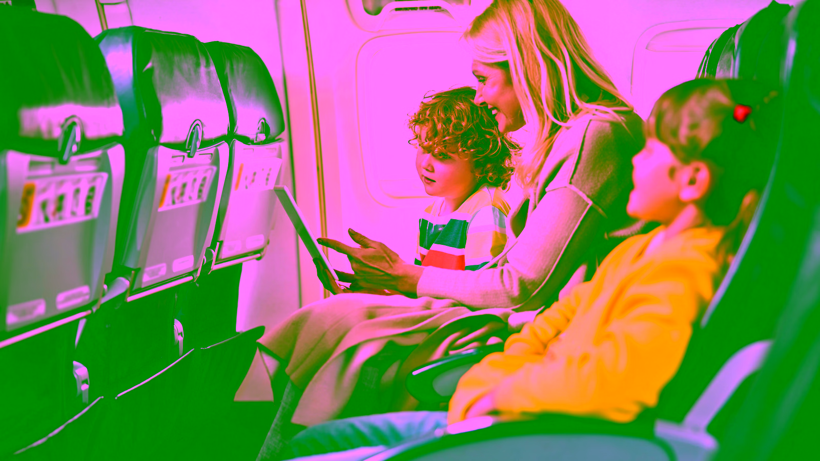 Family with two children using a tablet during a flight.