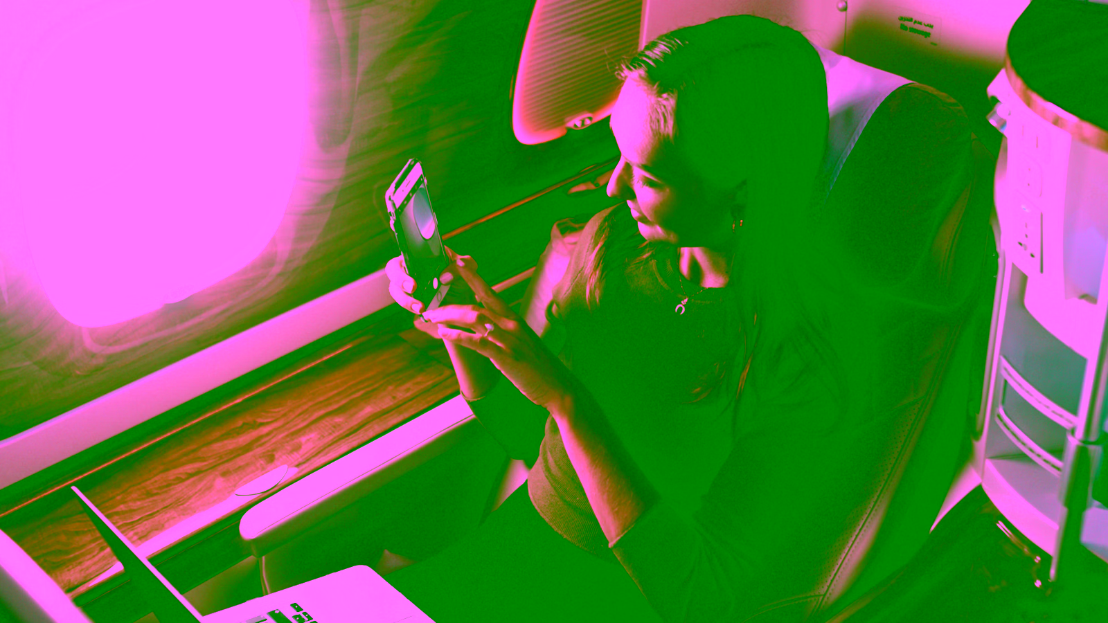 Woman using smartphone in a business class airplane seat