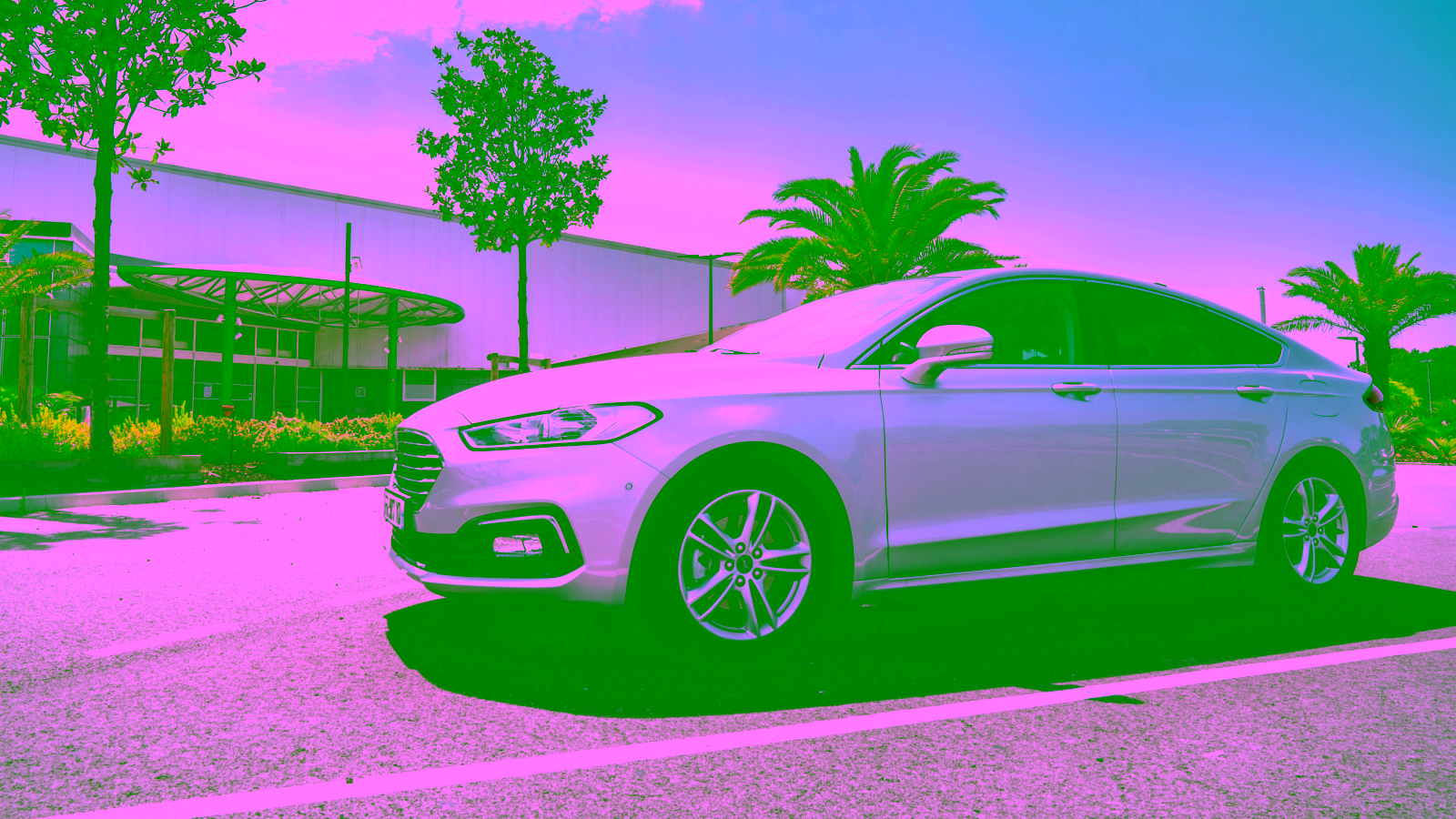 White sedan parked outside a modern building