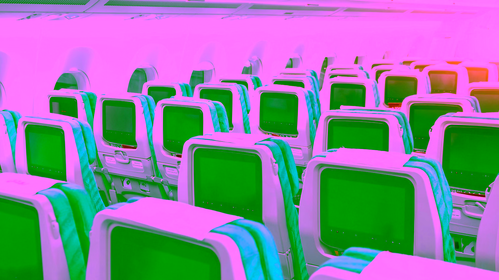Airplane cabin with rows of passenger seats and screens