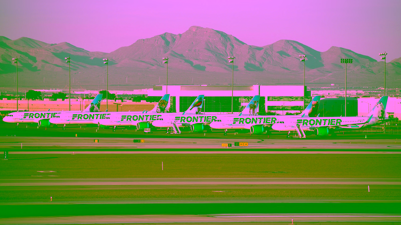 Frontier Airlines planes at airport with mountains in background