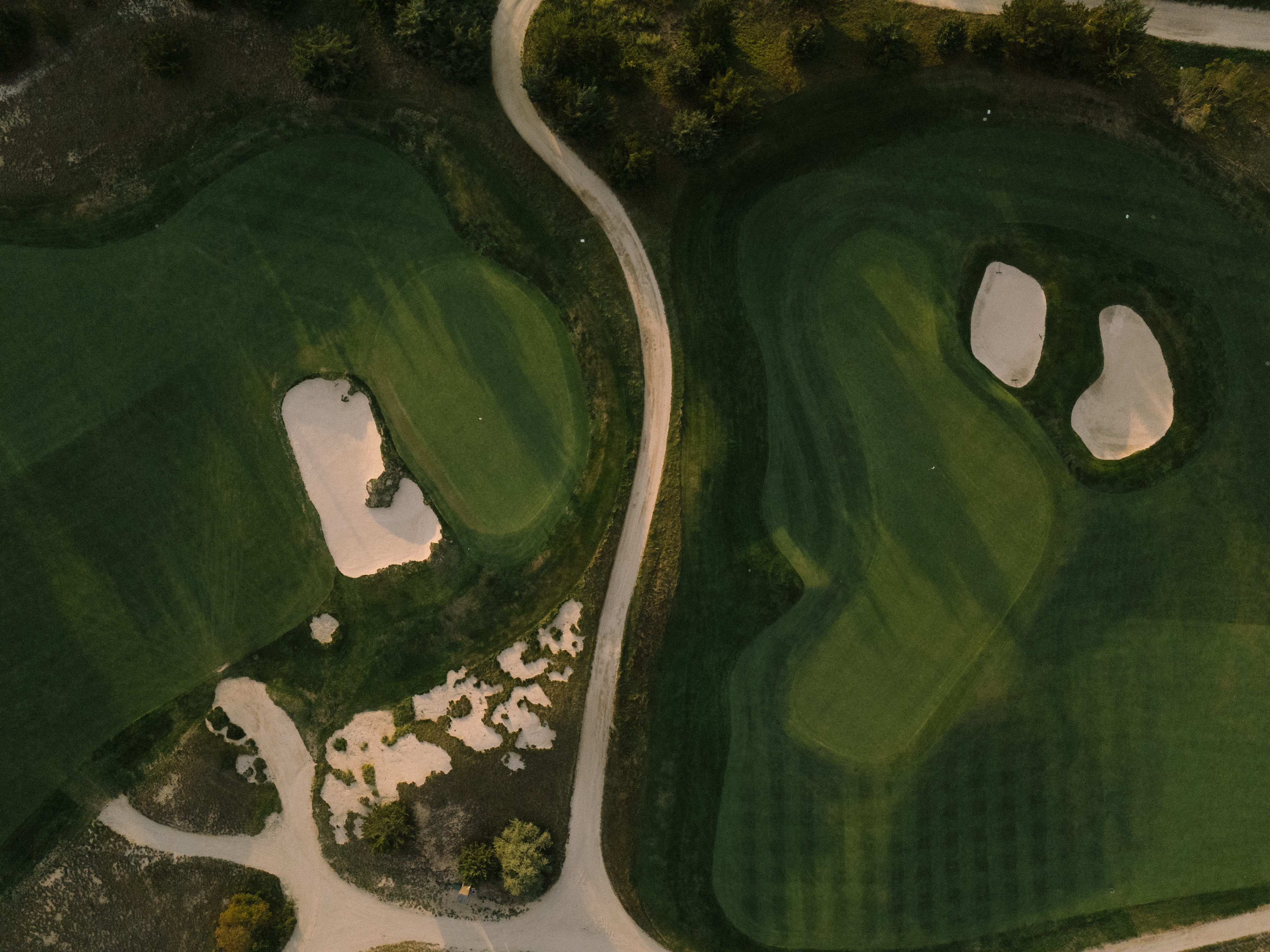 Aerial view of Laurel Links Country Club showing two greens with sand bunkers and a curved cart path between them.