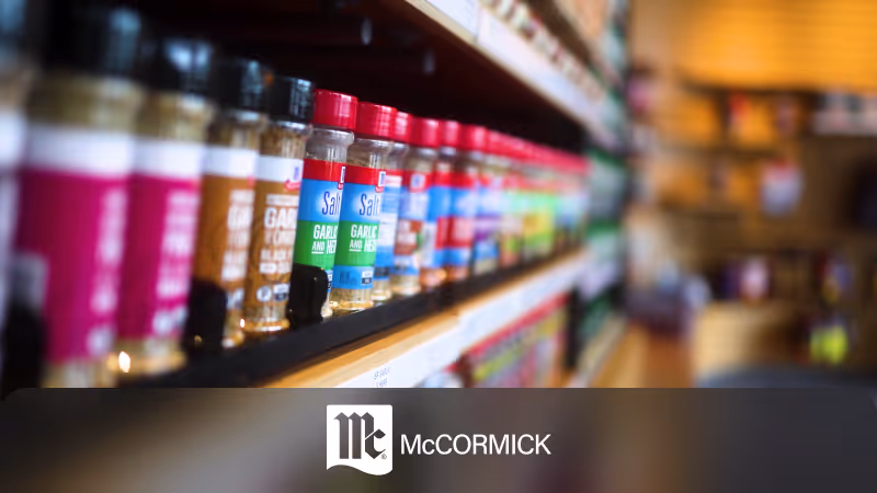 Shelf displaying various McCormick spice bottles with red and black caps in a store aisle.