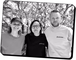 Trois personnes debout à l'extérieur avec des arbres en arrière-plan, souriant à la caméra.