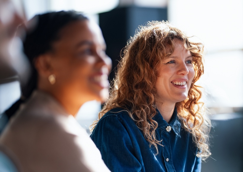Two women sitting together, both smiling warmly.