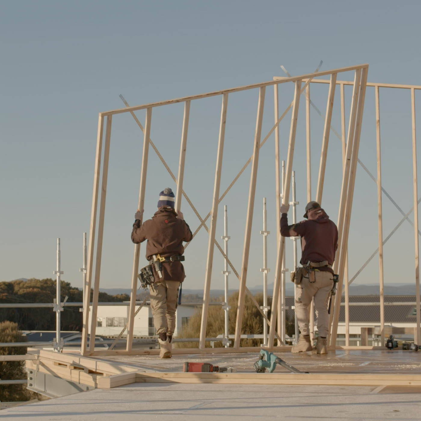 Two people lifting up a wooden frame.