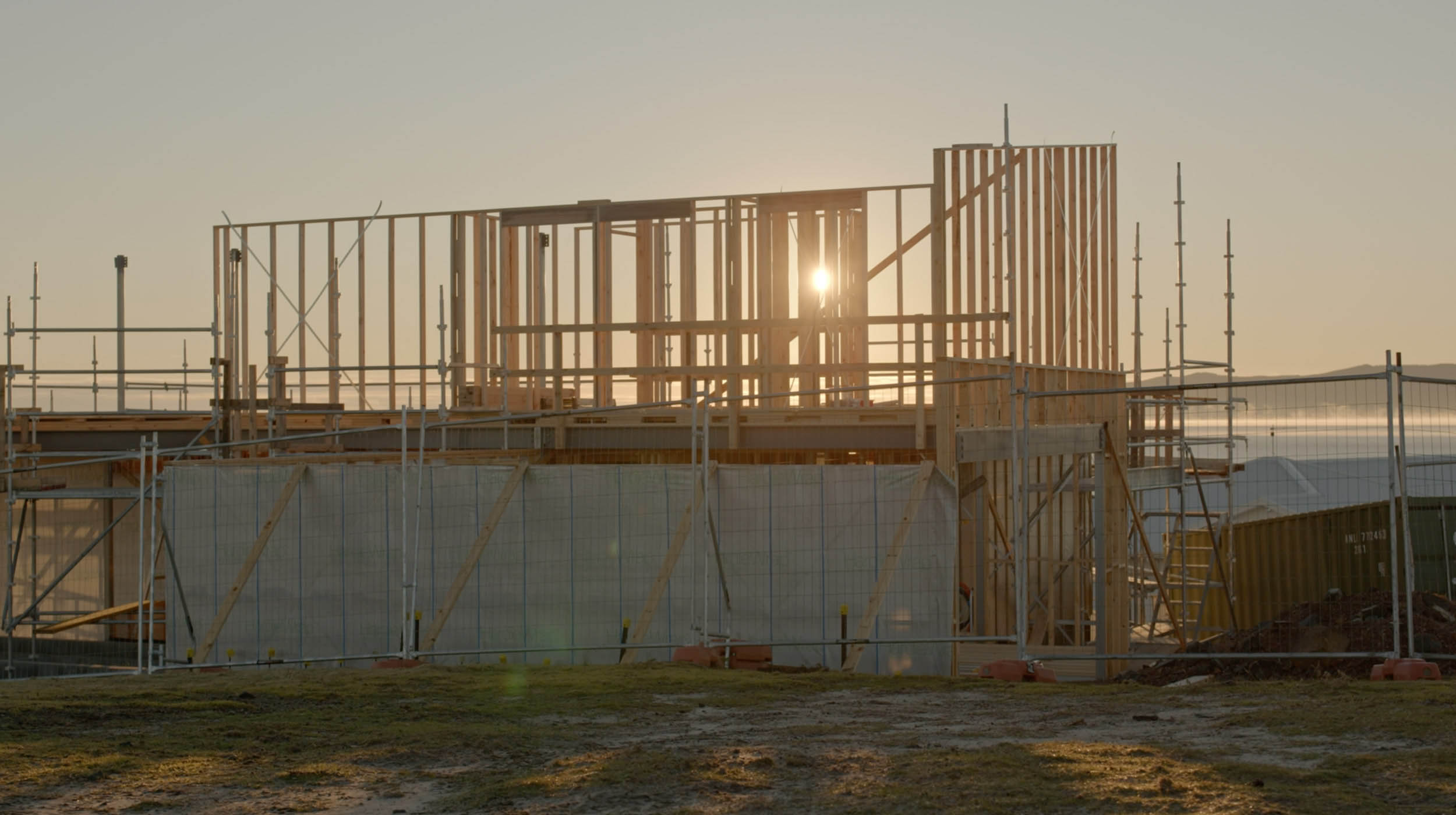An image of a house frame with a sunset overlooking it.