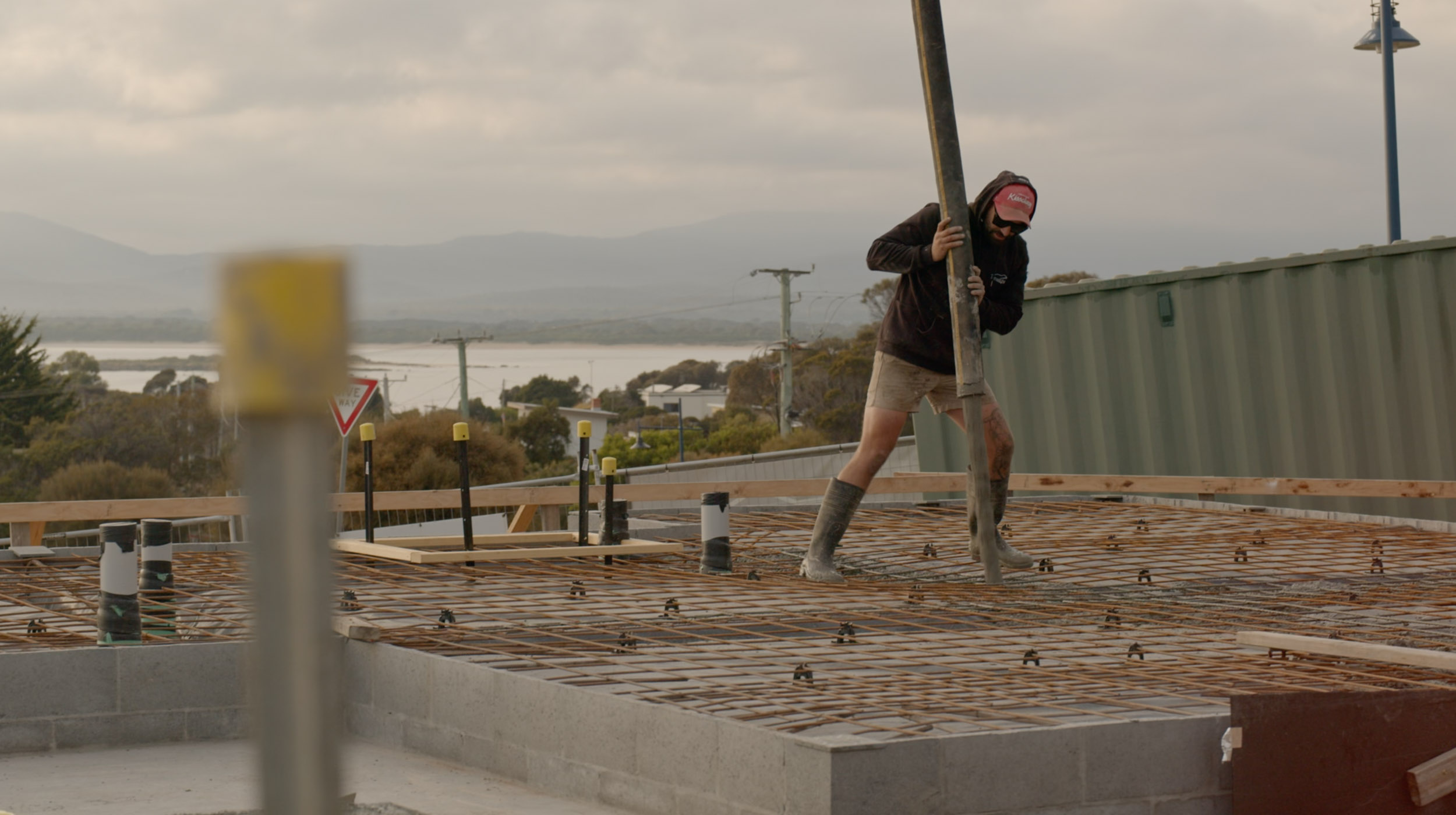 A person guiding the concrete into the reo mesh