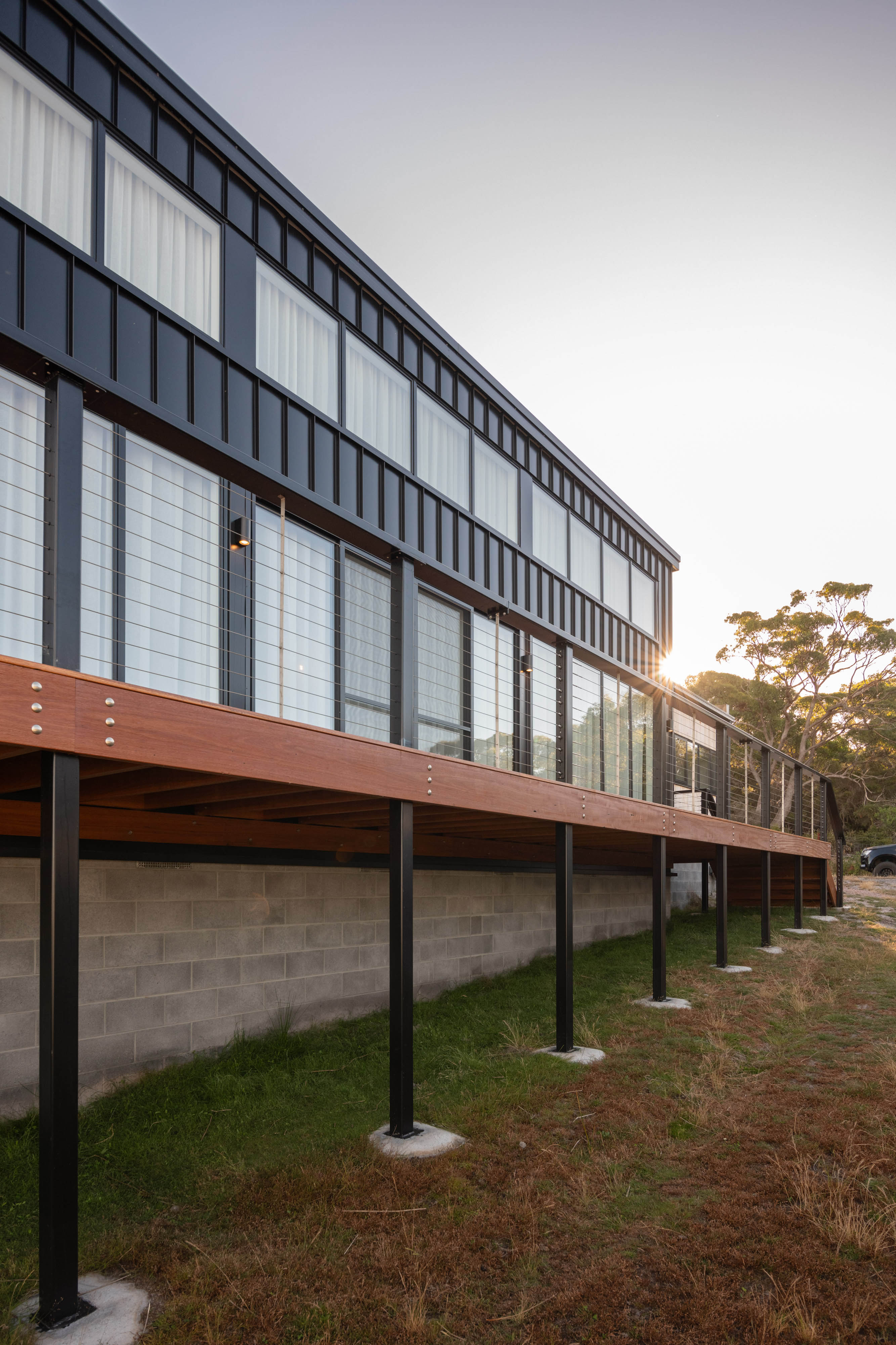 External image of a white coloured house with large windows with an orange coloured deck.
