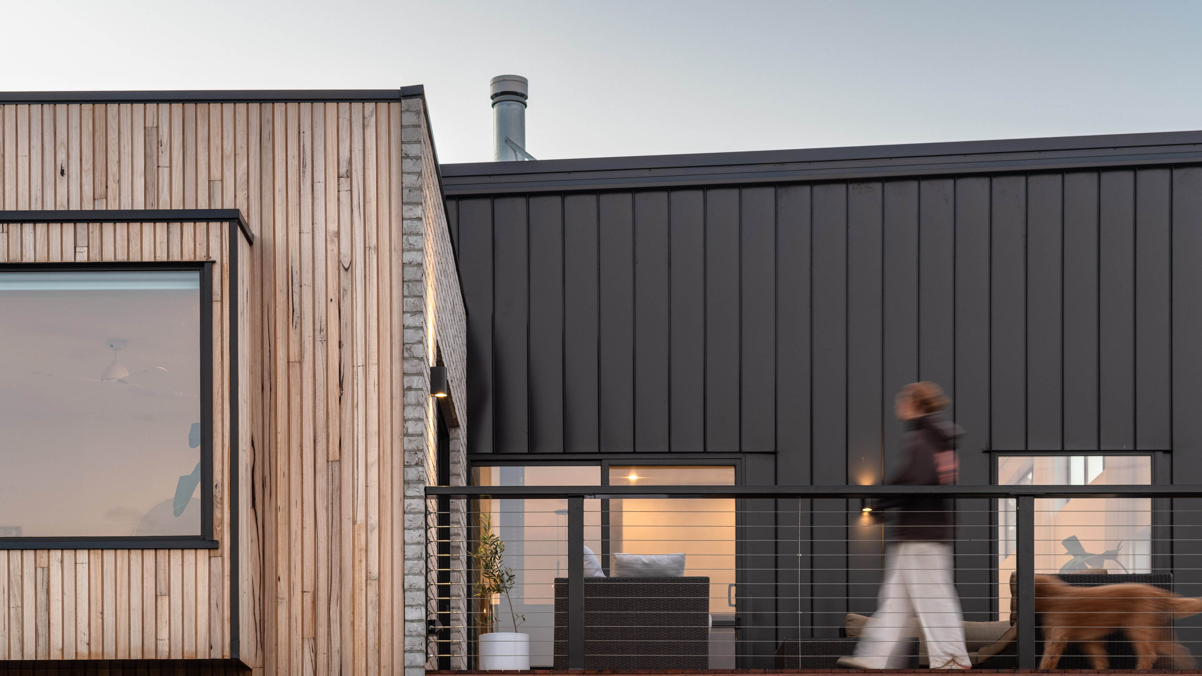 External image of a white coloured house with large windows with a nice sunset.