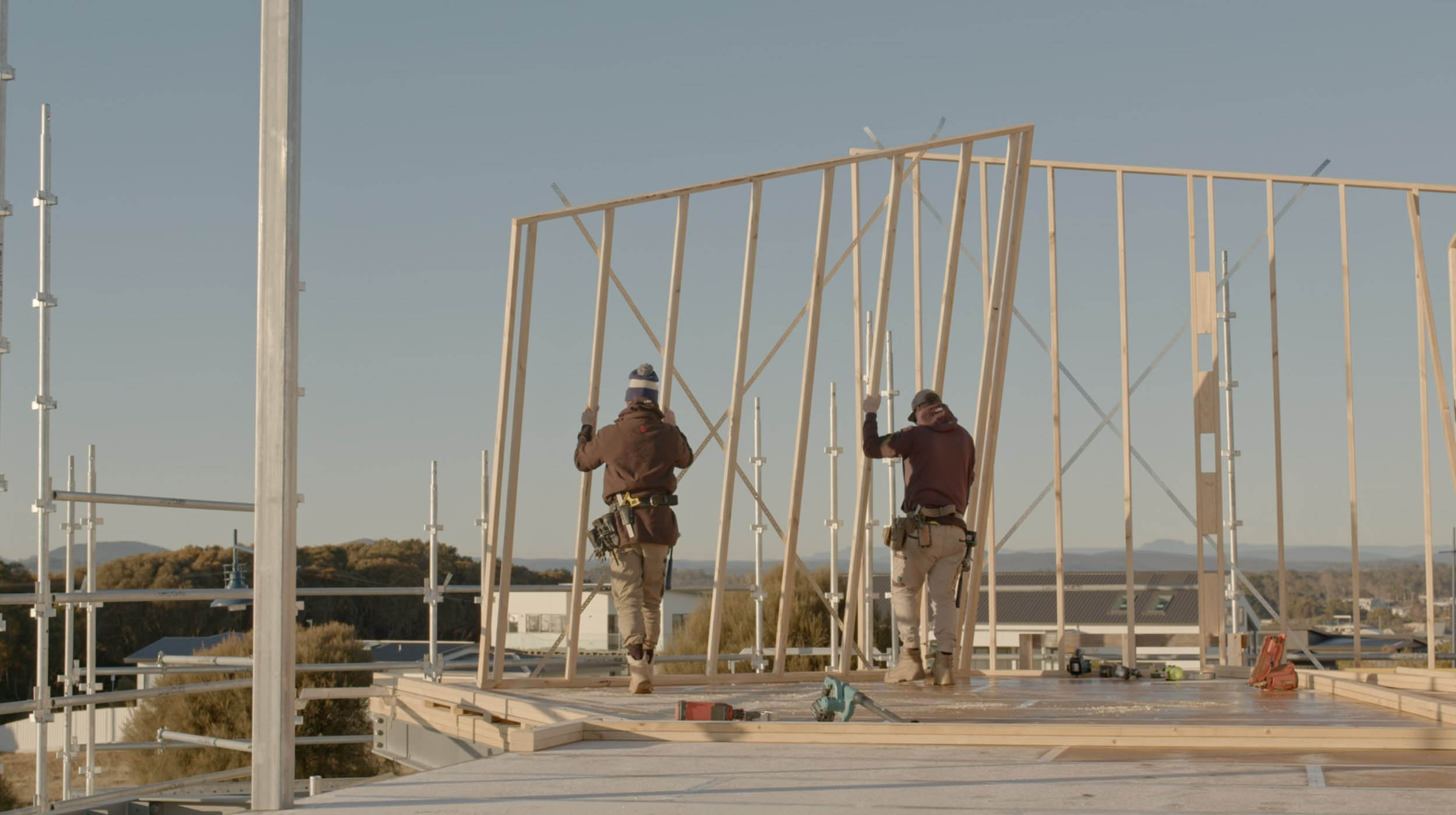 Two people lifting up a wooden frame.