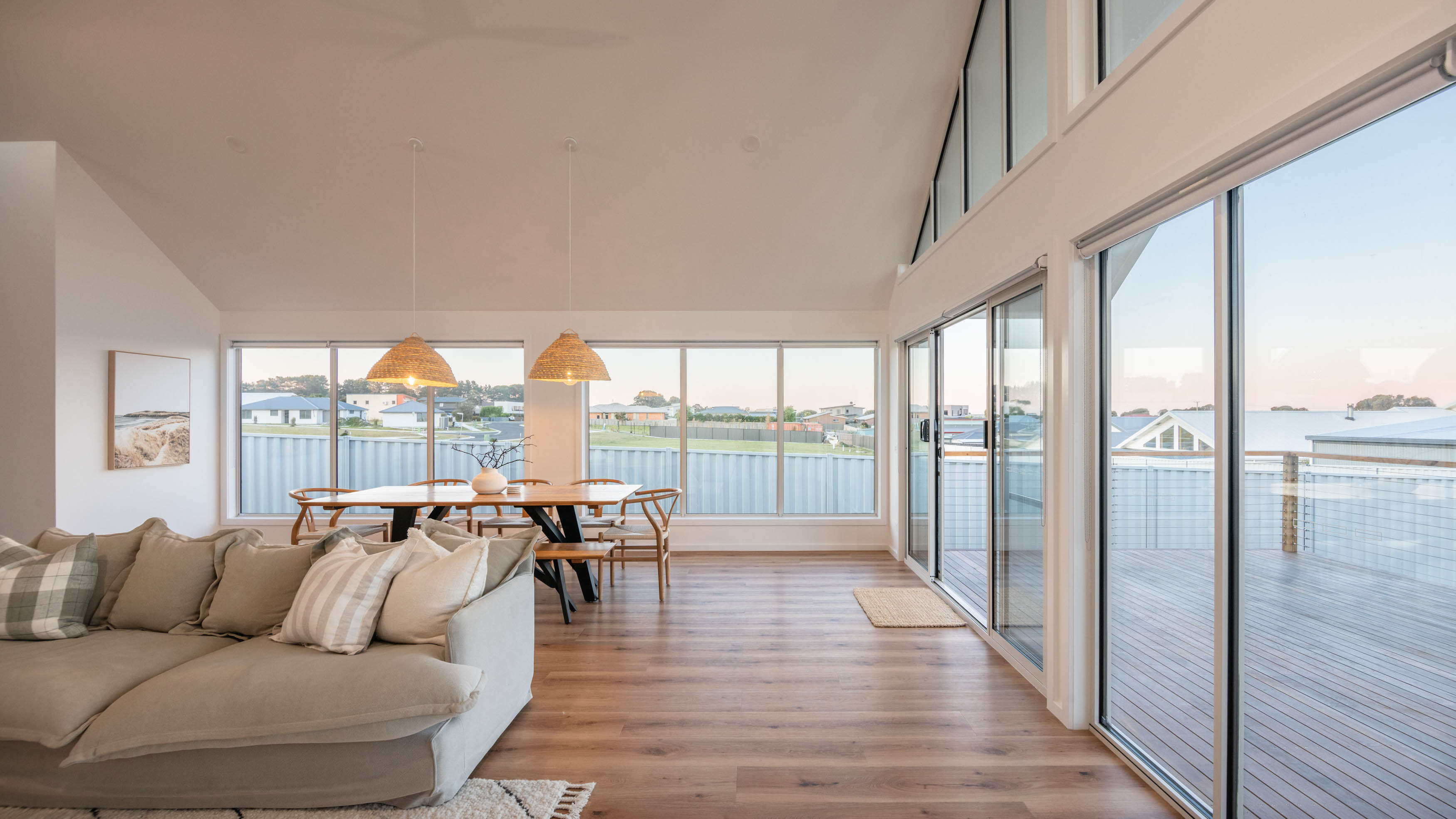 Lounge room with a nice beige sofa and polished floorboards with nice big windows.