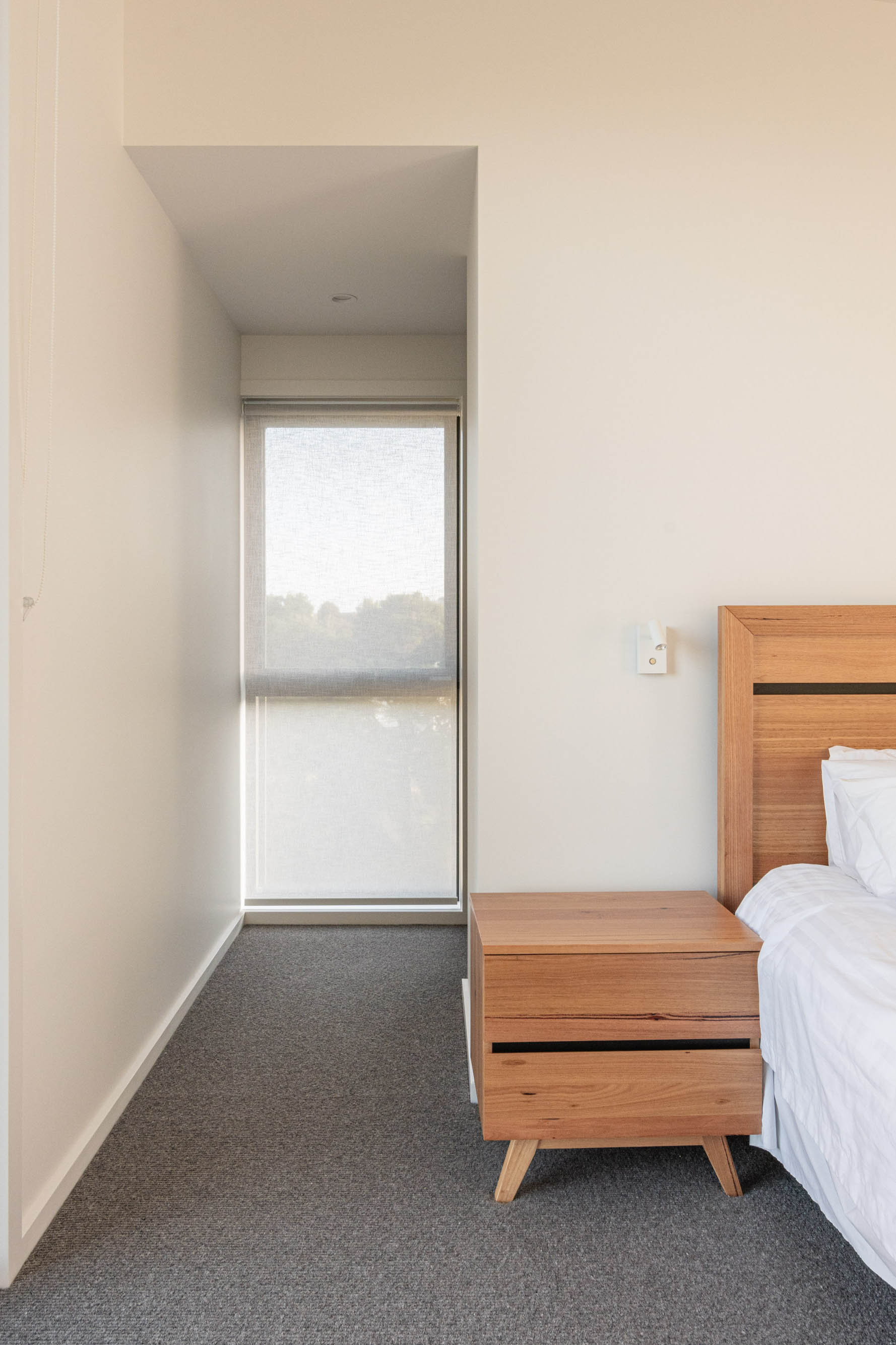 Bedroom with white bed sheets and a hazelnut coloured wooden bed base.