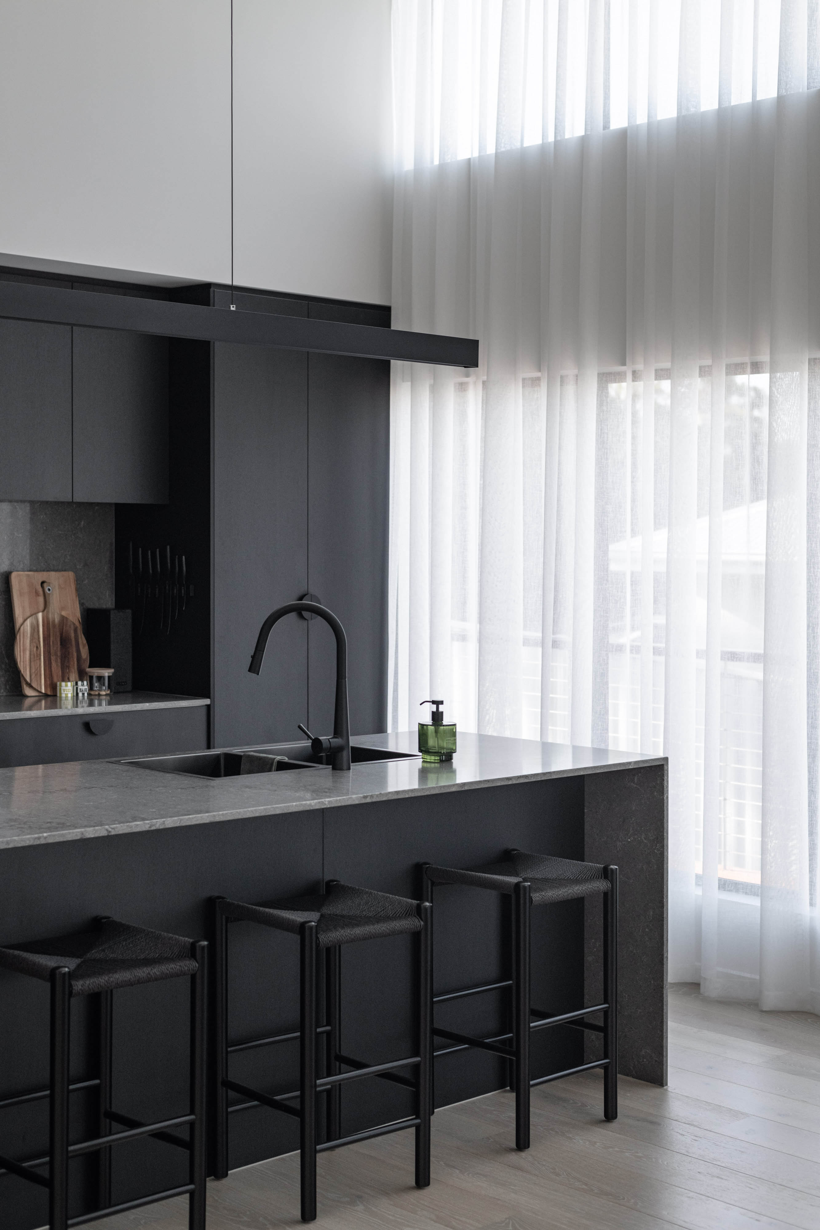 Kitchen with a black colour scheme and white bench tops.
