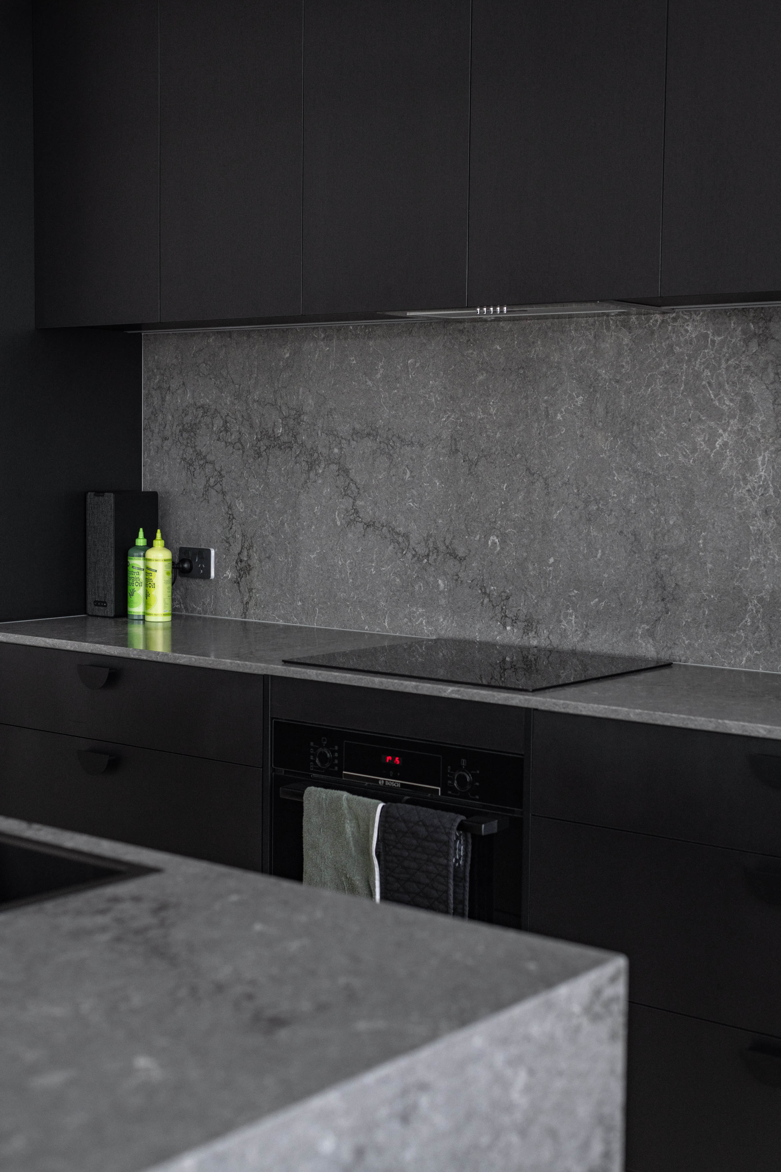 Kitchen with a black colour scheme and white bench tops.