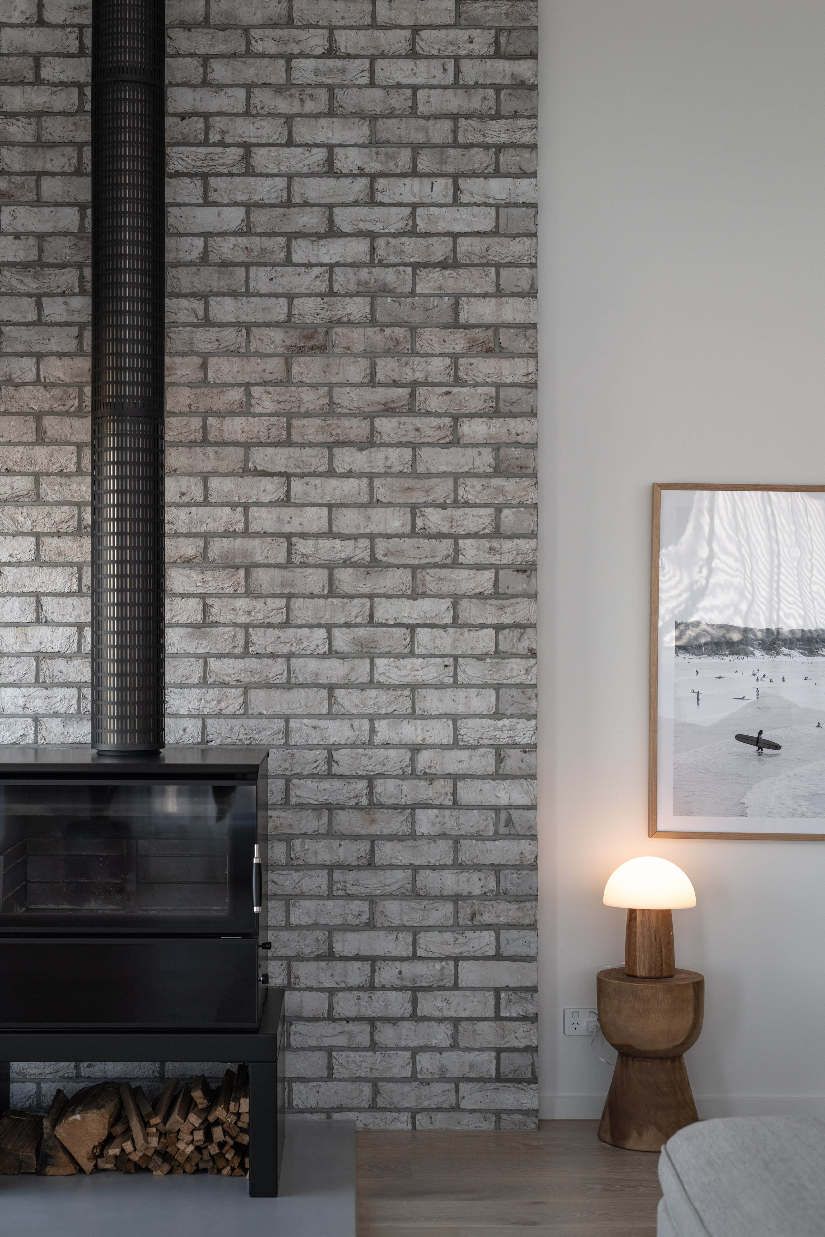 Lounge room with a fireplace and white stone bricks and a white wall.