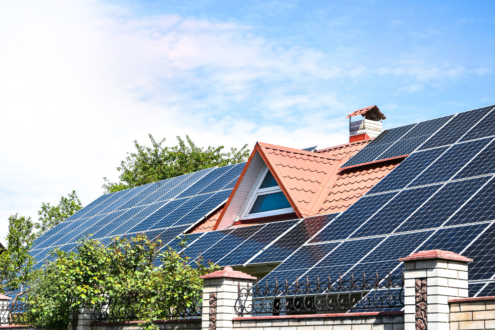 Einfamilienhaus mit rotem Ziegeldach und großflächiger Photovoltaikanlage, aufgenommen bei Sonnenschein – Symbol für nachhaltige Energie und Strom vom eigenen Dach