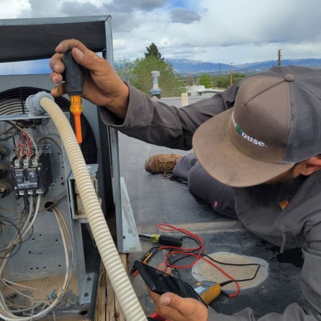 Technician repairing a rooftop air conditioning unit.