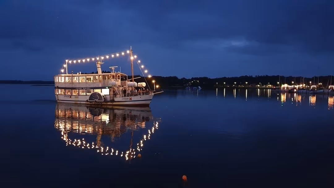En stor båd, der flyder på toppen af ​​en sø om natten.