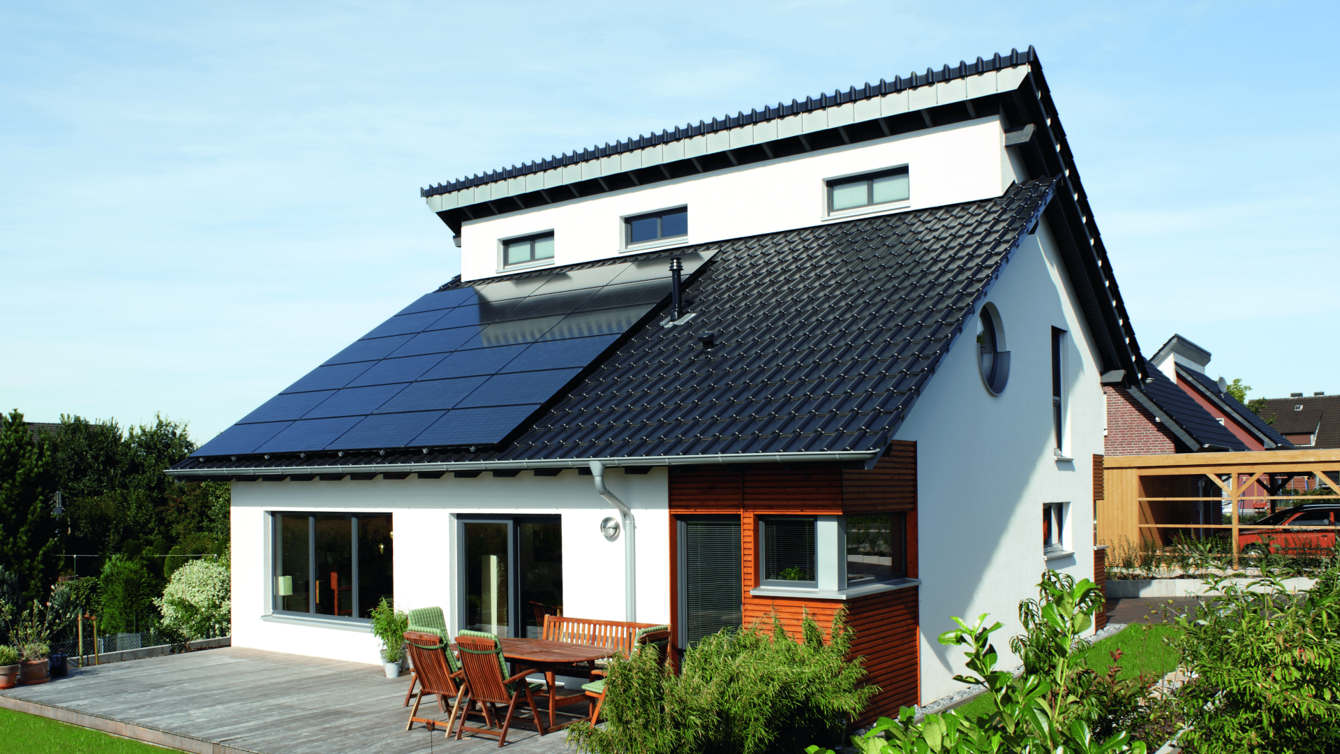 Einfamilienhaus mit Viessmann Vitovolt 300-DG Photovoltaikanlage auf dem Schrägdach – schwarze Glas-Glas-Module vollflächig installiert, modernes Wohnhaus mit Carport im Hintergrund