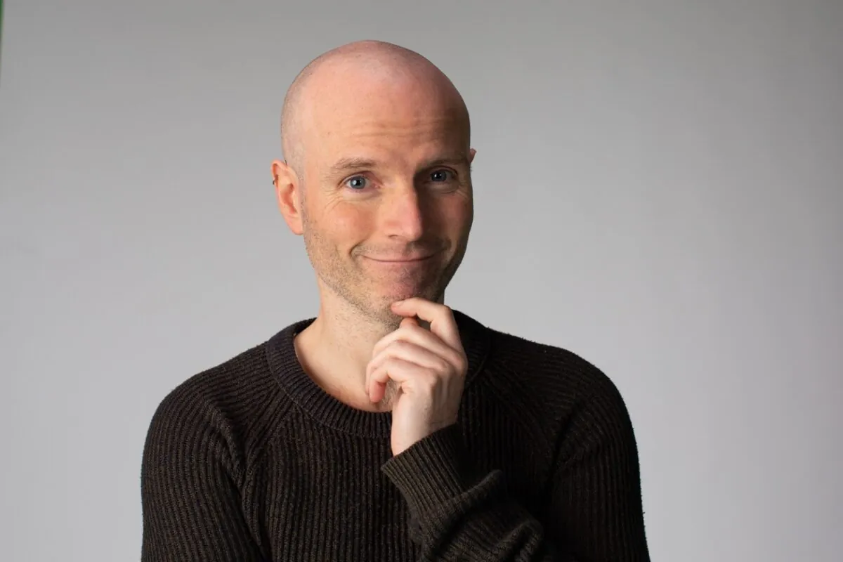 A bald person with his hand on his chinDescription automatically generated