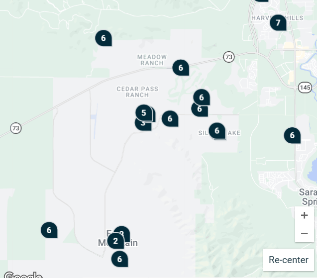 A white plastic bag filled with dog poop on patchy dry grass, with a small rake and yellow dustpan nearby.