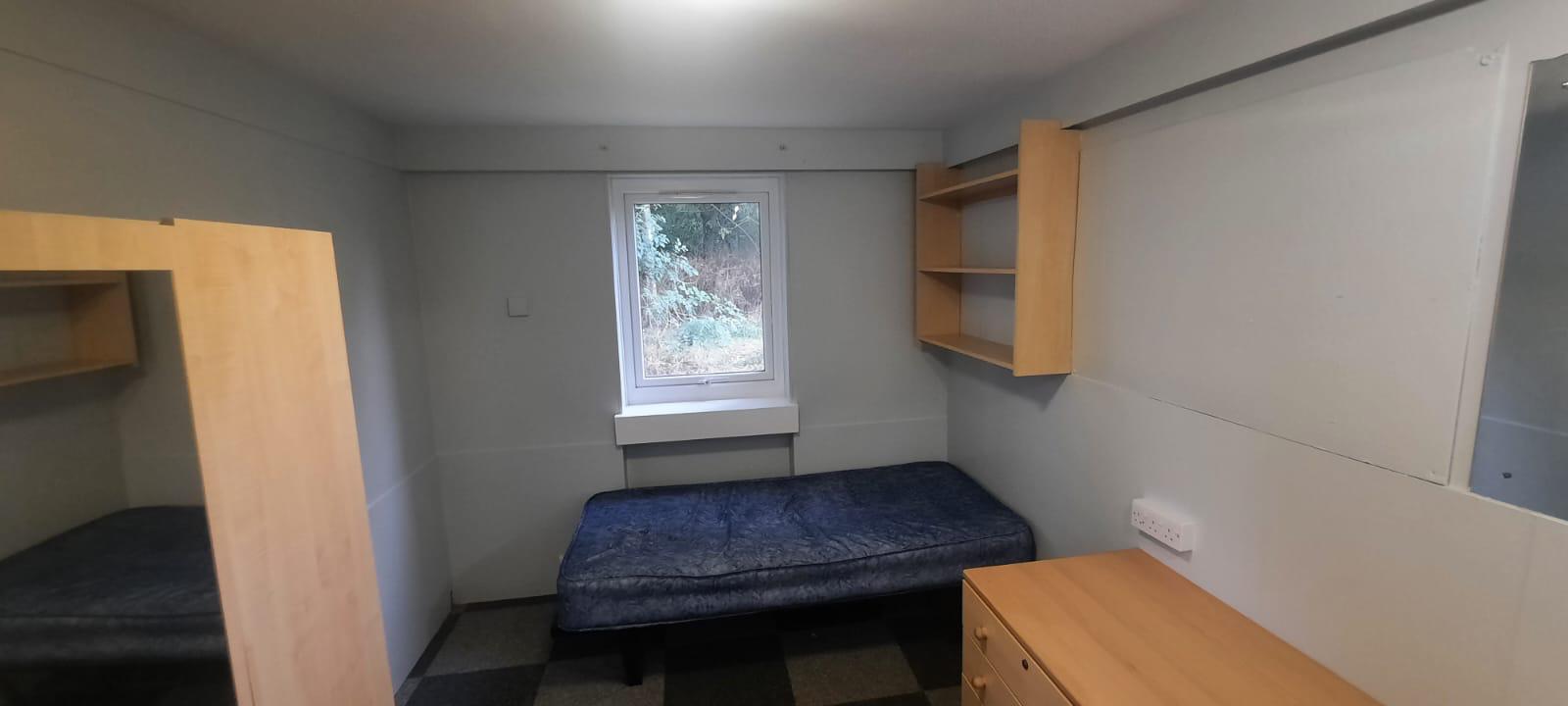 Refurbished university accommodation bedroom with fitted shelving and desk
