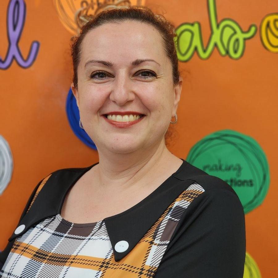 Victoria Rybalskiy smiling in front of colorful school display