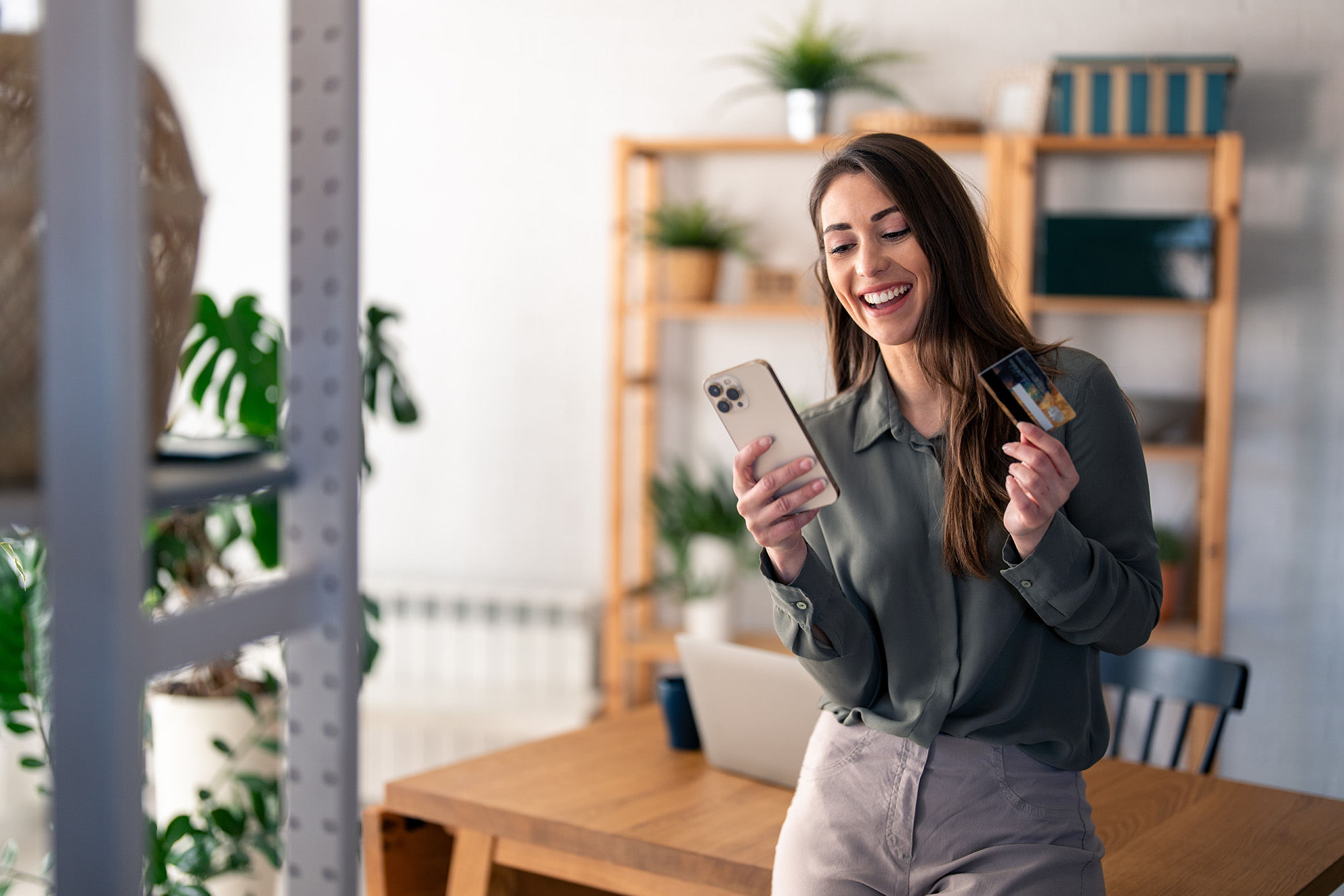 A picture of a woman using her smartphone and holding a credit card.