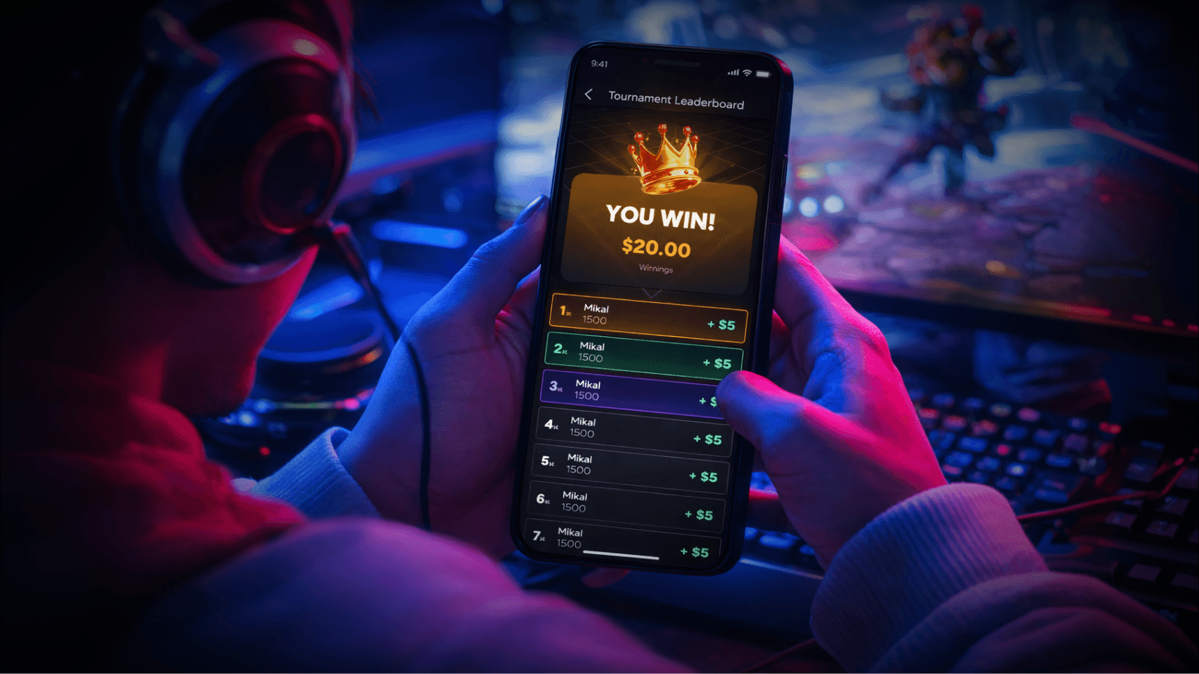 Person wearing headphones holding a smartphone displaying a tournament leaderboard screen with 'YOU WIN! $20.00' and multiple entries named Mikal ranked 1st to 7th.