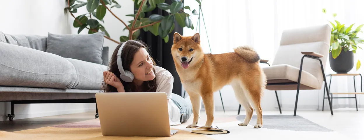 A man and a woman sitting on the grass with two dogs.