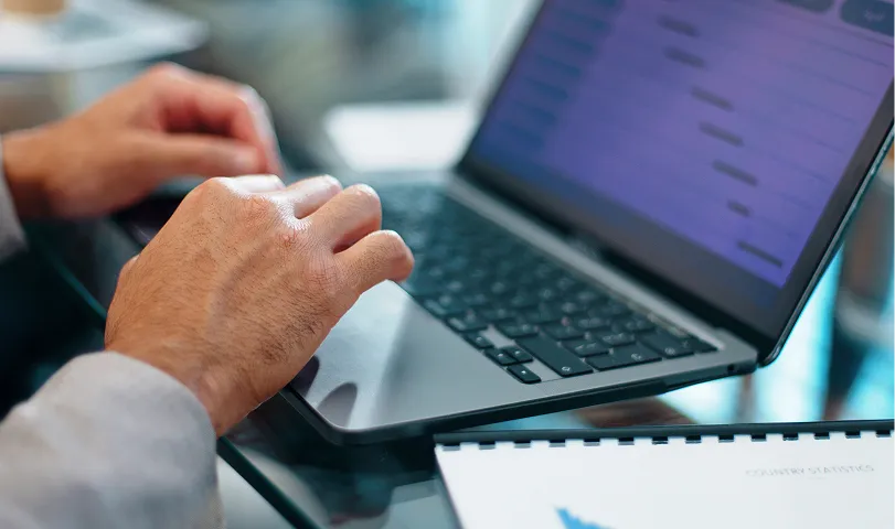 A man sitting at a table working on a laptop.