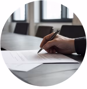 Hand som skriver på ett dokument vid ett ljust skrivbord