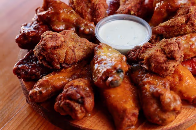 A plate of fried chicken wings with a dipping sauce.