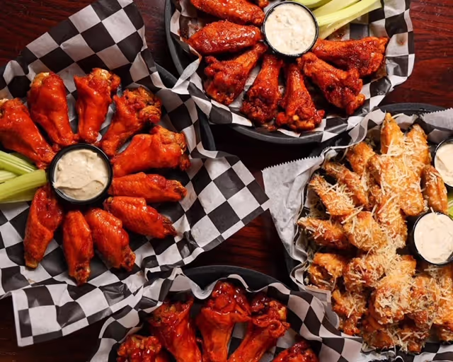A plate of wings with a side of ranch dressing.