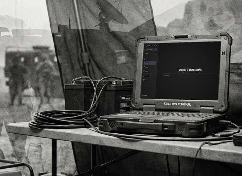 A laptop labelled "Field OPS terminal", on a desk that is out on the field.
