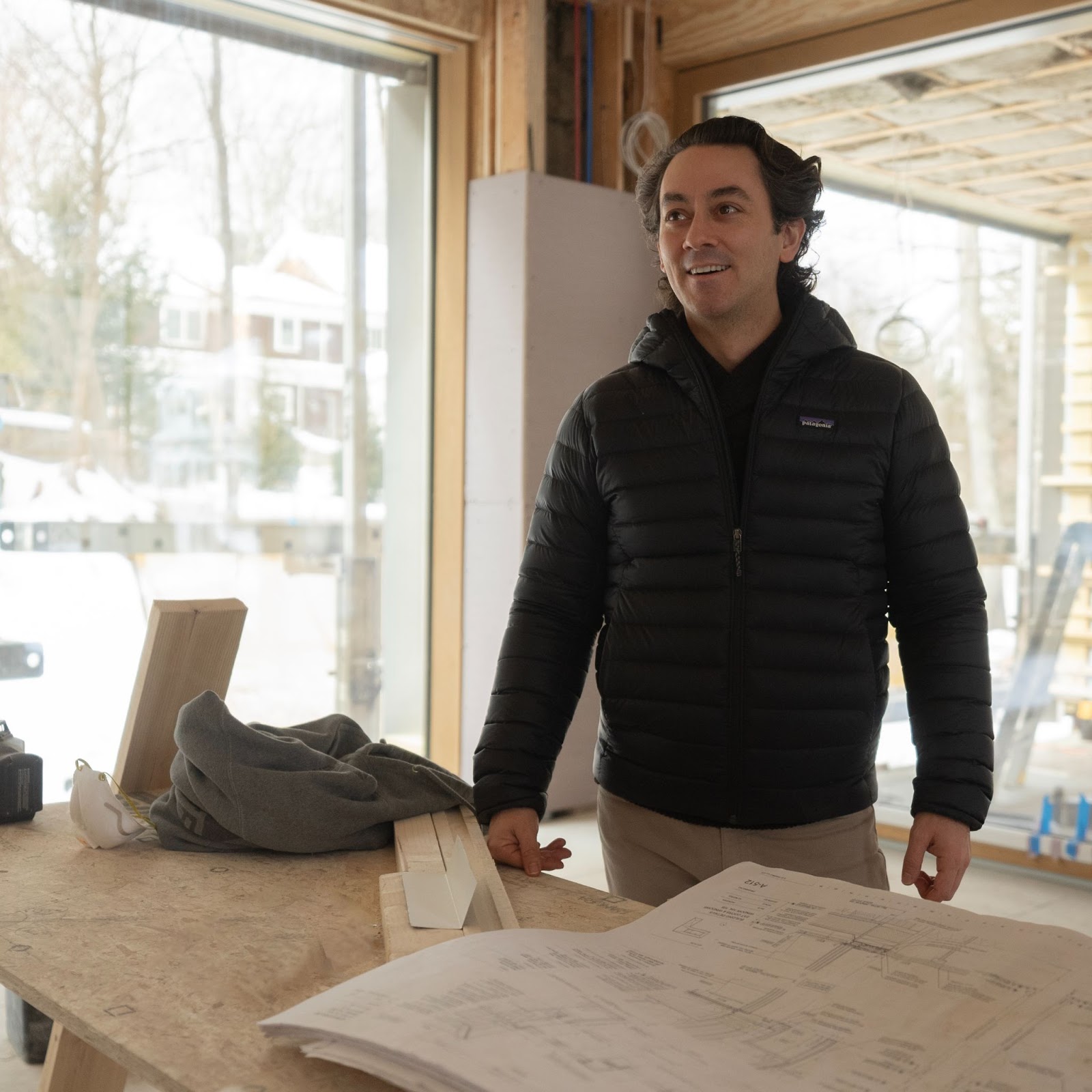Man reviewing construction plans inside a partially built home.