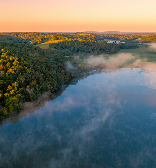 An aerial view over a river with a wooded banks