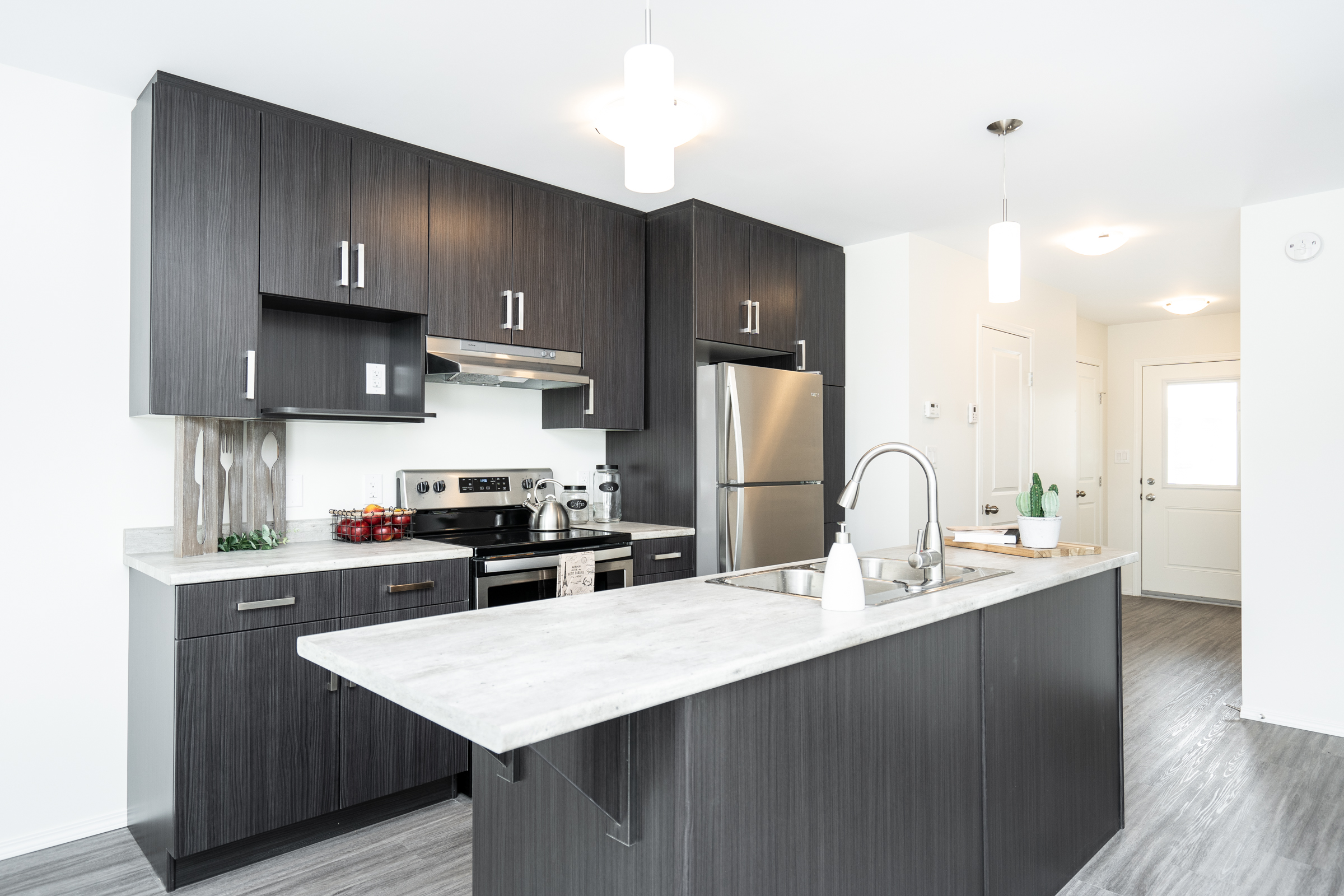 Harvest Gate kitchen with dark cabinets, stainless steel appliances, large island sink, and modern pendant lighting