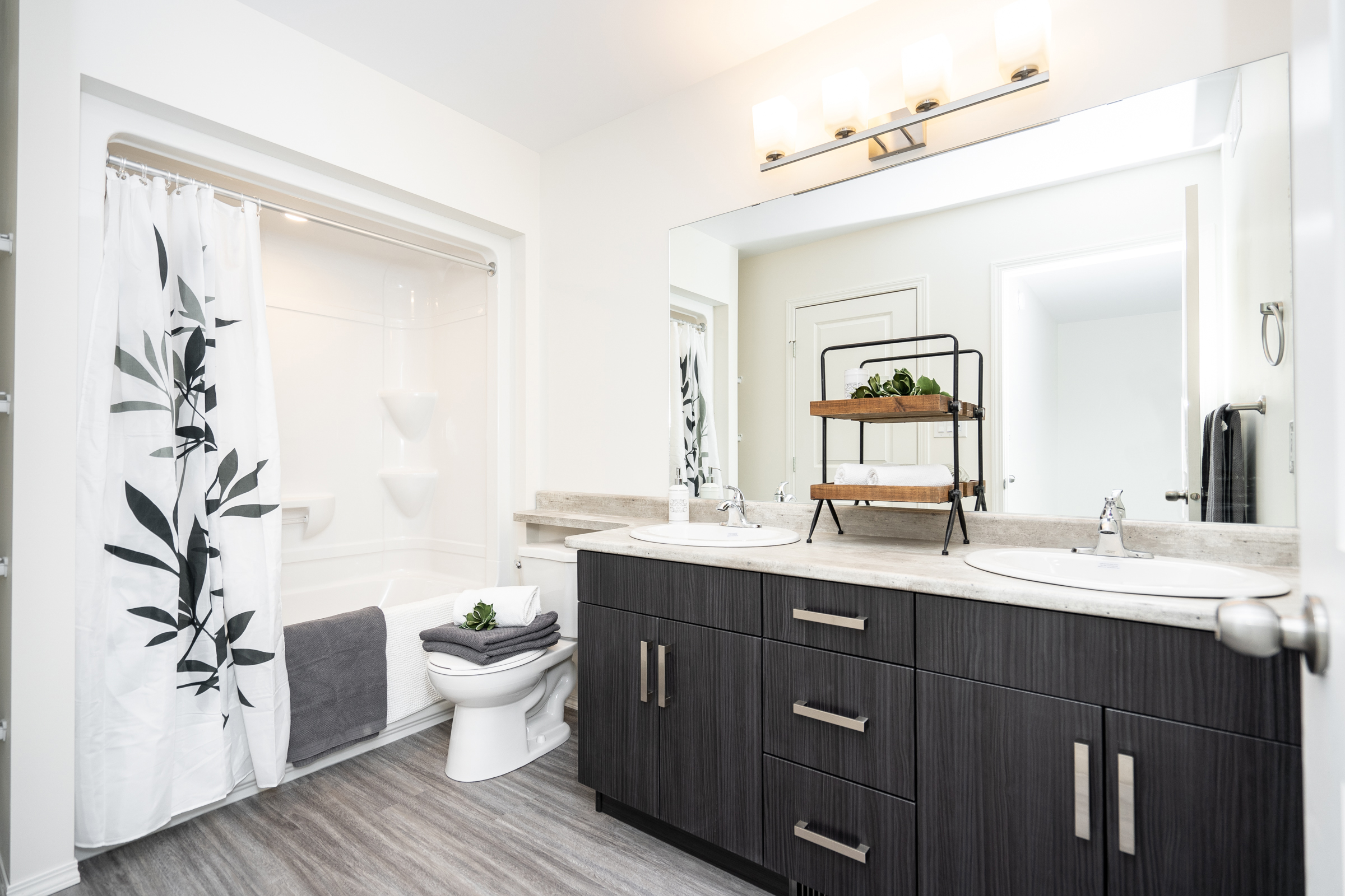 Harvest Gate bathroom with double-sink vanity, large mirror, dark cabinets, and tub-shower combination