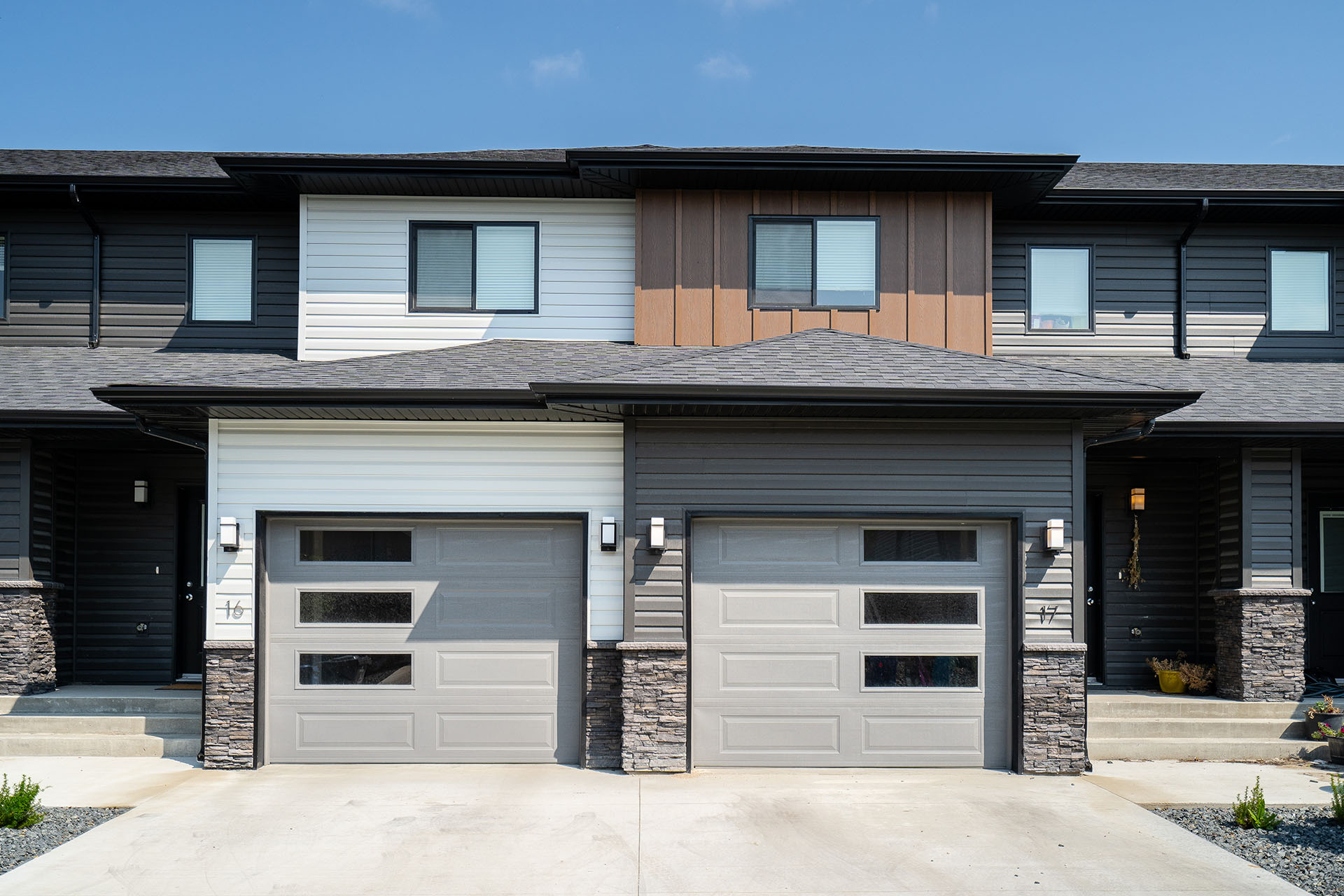 Harvest Gate townhome exterior in Oak Bluff, MB with attached garages, modern siding, stone accents, and private driveways