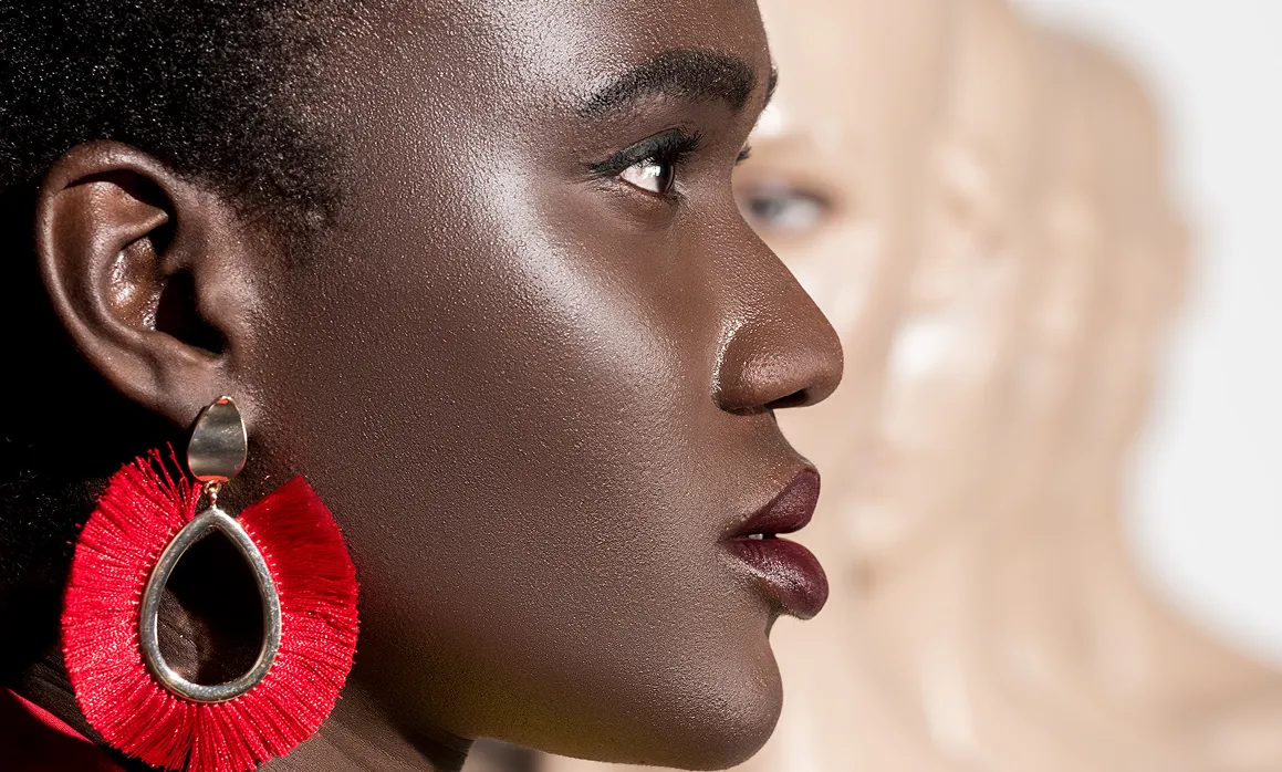 Profile of person with vibrant red statement earrings and dark lipstick