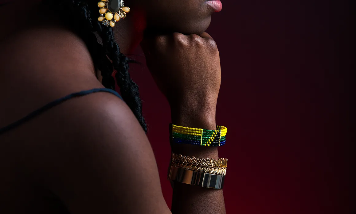 Closeup of wrist with colorful beaded bracelets and gold earring