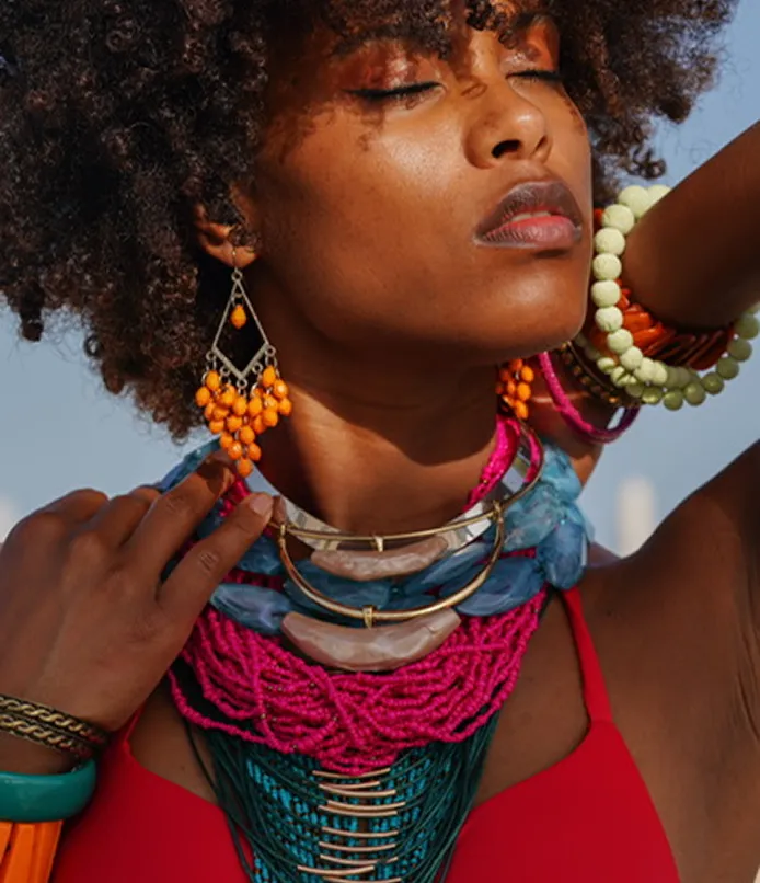 Woman with afro hair wearing vibrant beaded jewelry and red top