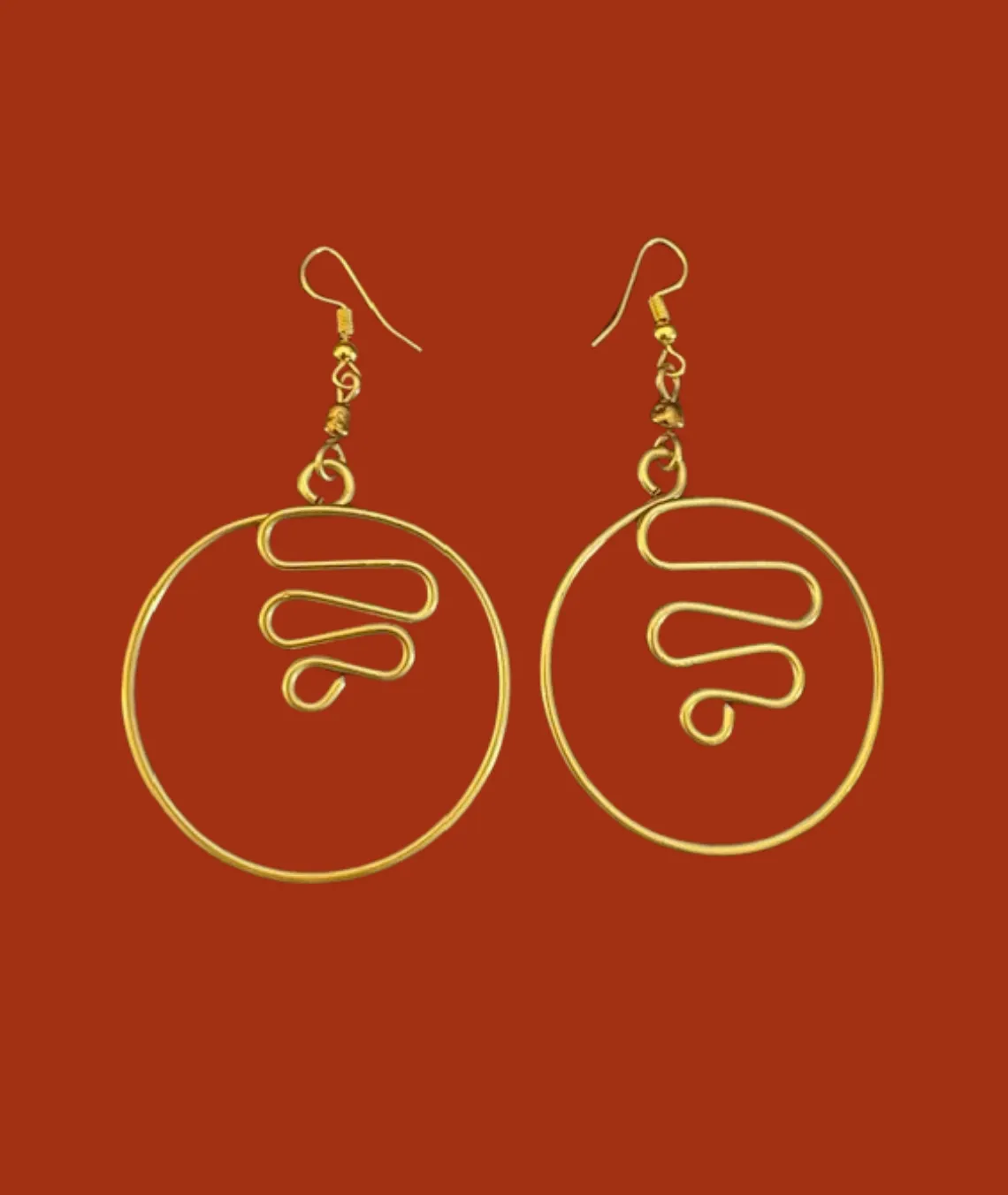 Gold circular wire earrings with wavy design on rusty red background