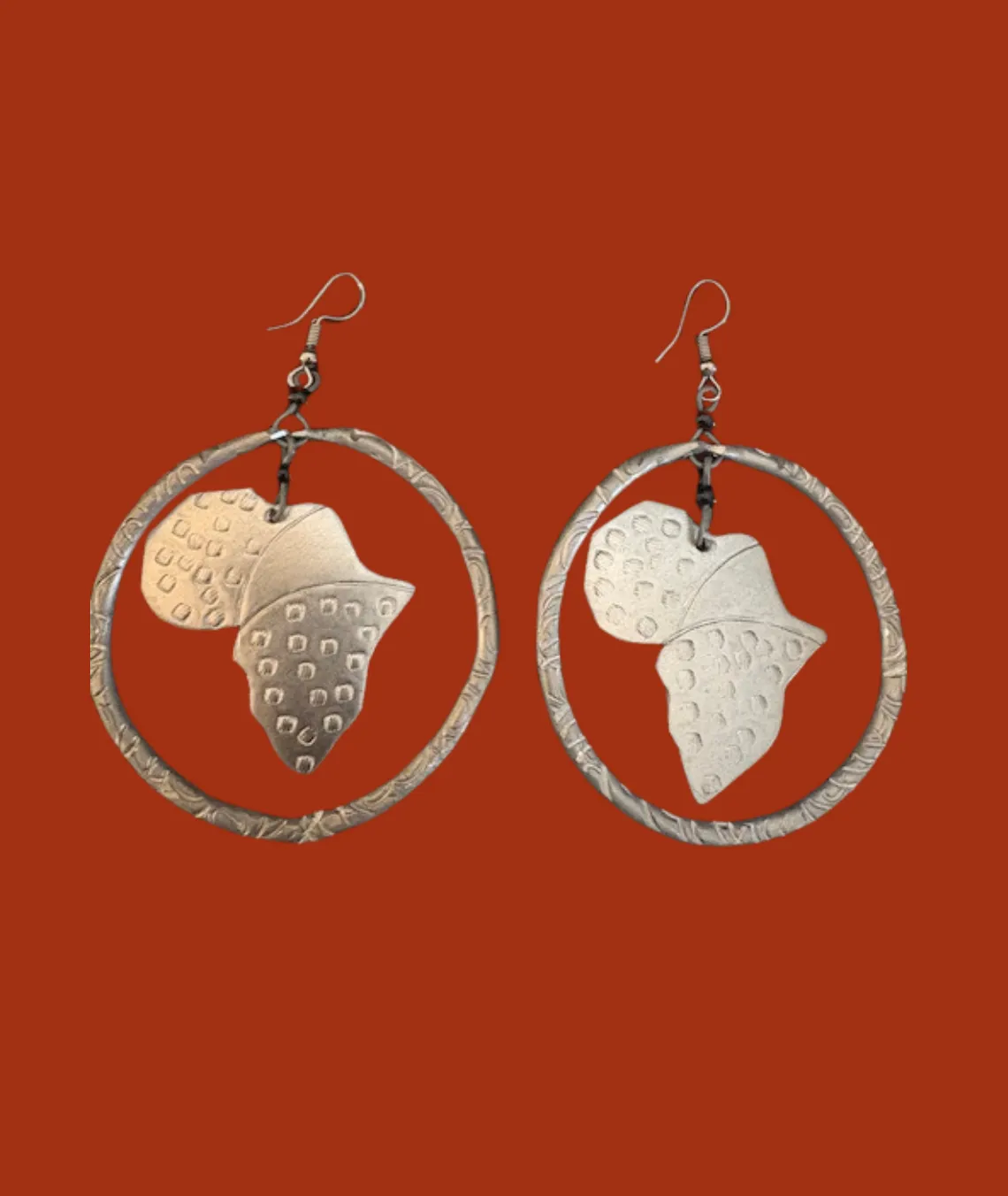 Silver Africa-shaped earrings with textured design on red background