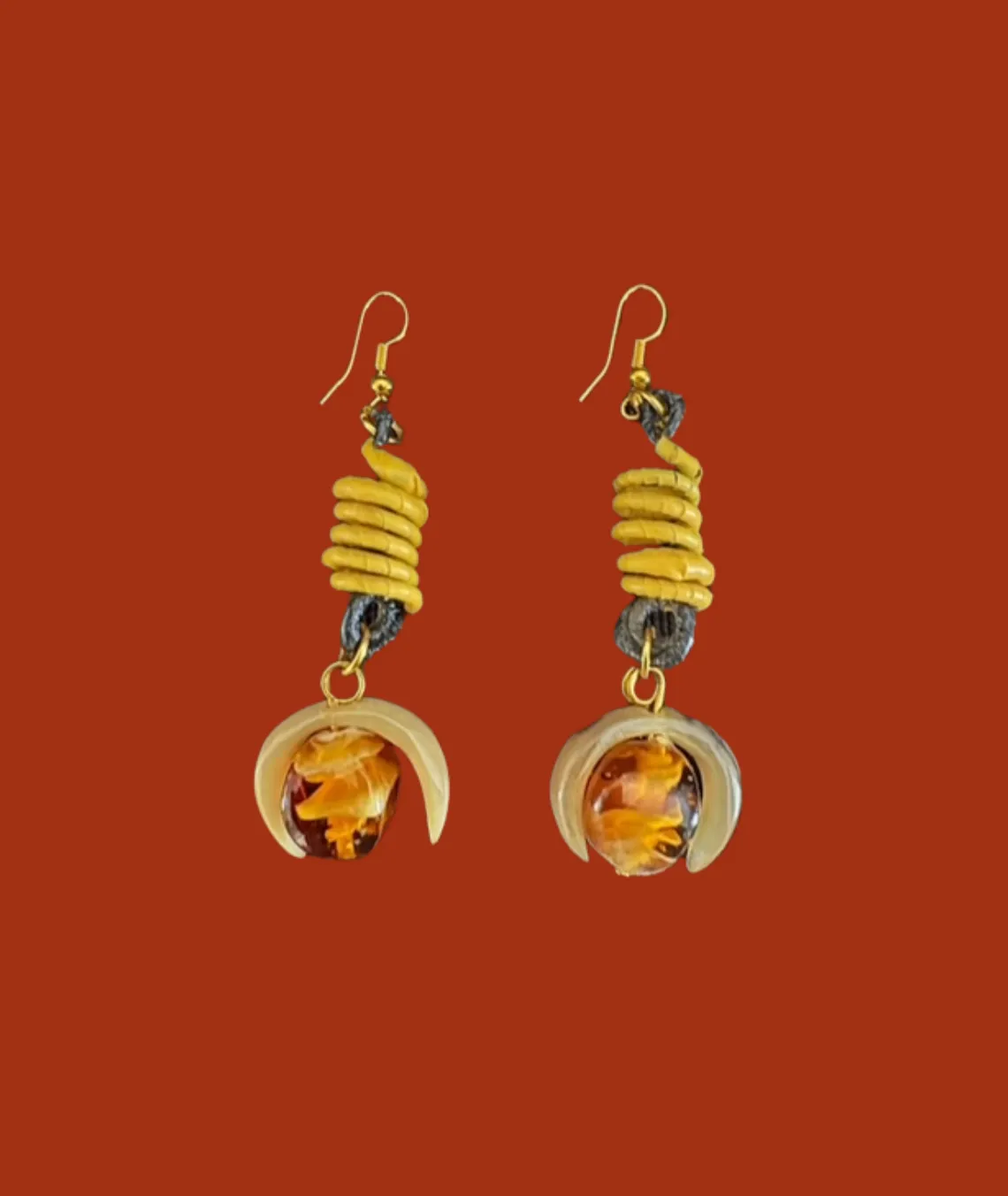 Yellow spiral earrings with amber-like stones on red background