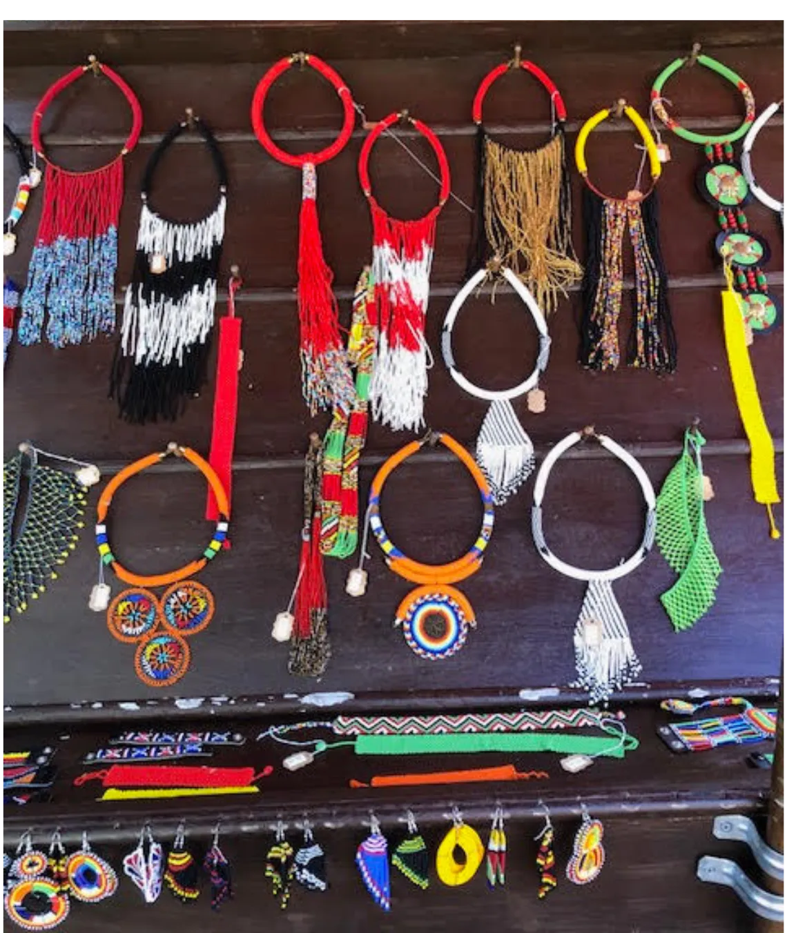 Colorful traditional African beaded necklaces and jewelry displayed on wooden board