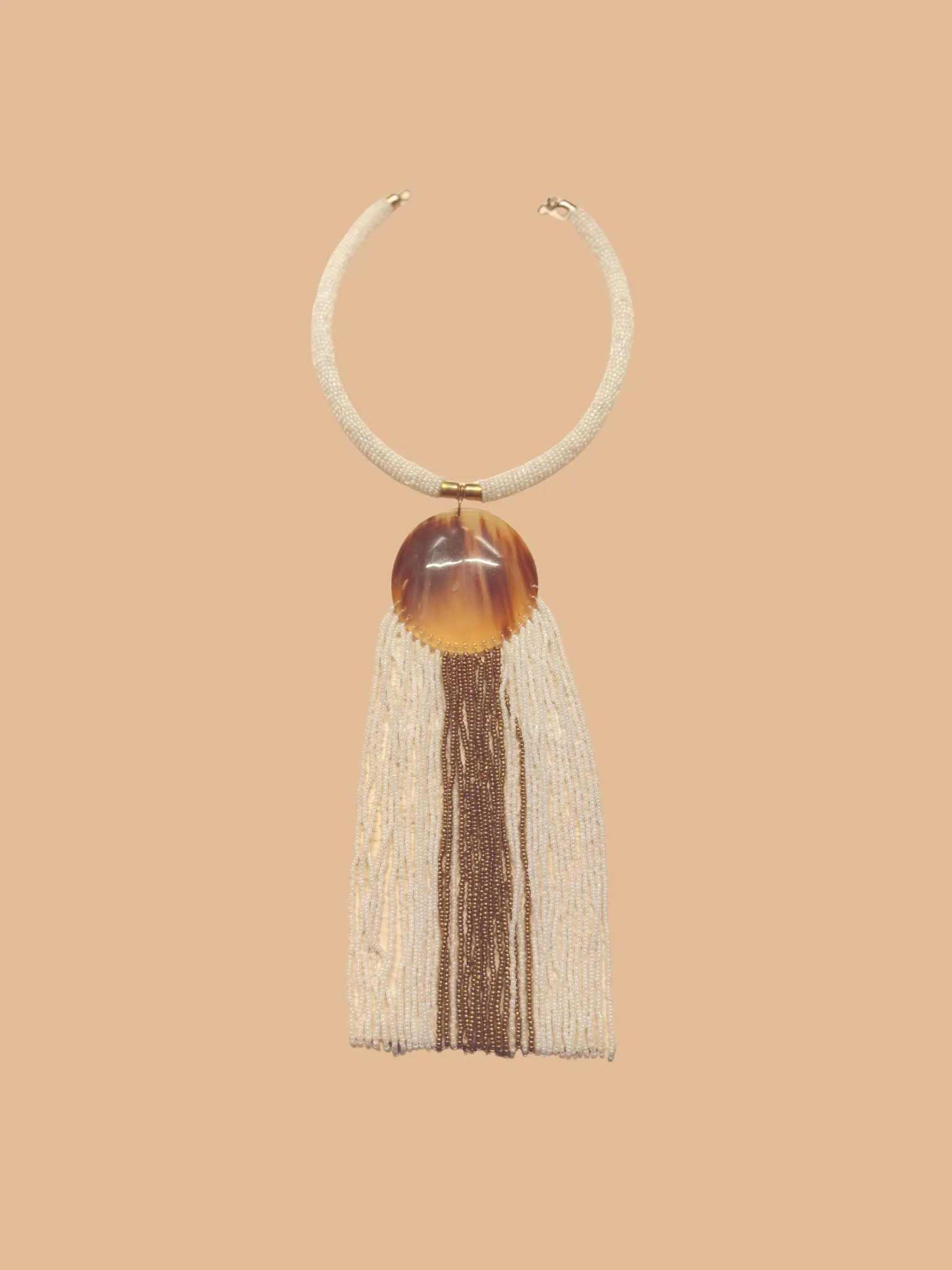 Beaded tassel necklace with amber-like pendant on neutral background