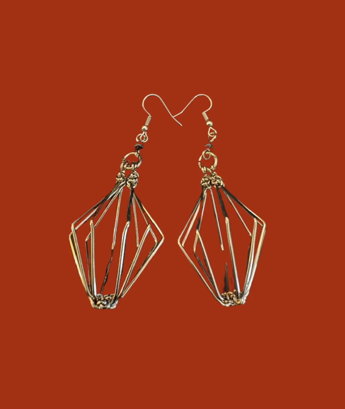 Geometric wire earrings with intricate angular design on red background